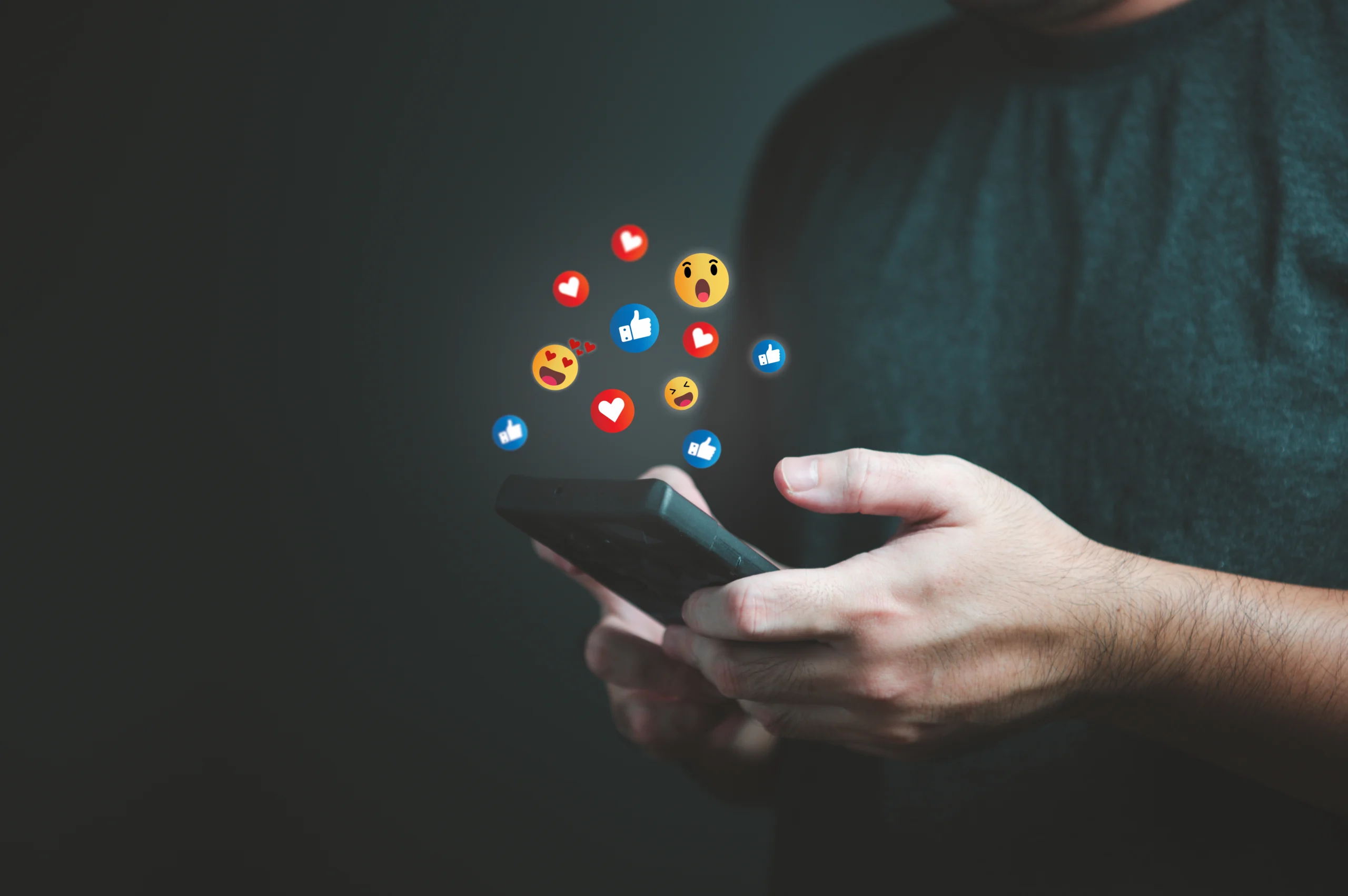 person holding a phone with emoji graphics coming out of the screen